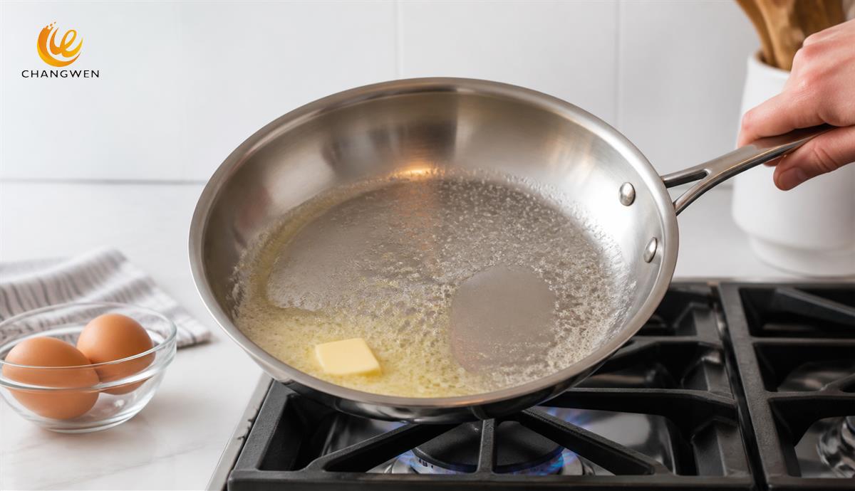 Butter foaming in a preheated stainless steel frying pan before cooking eggs