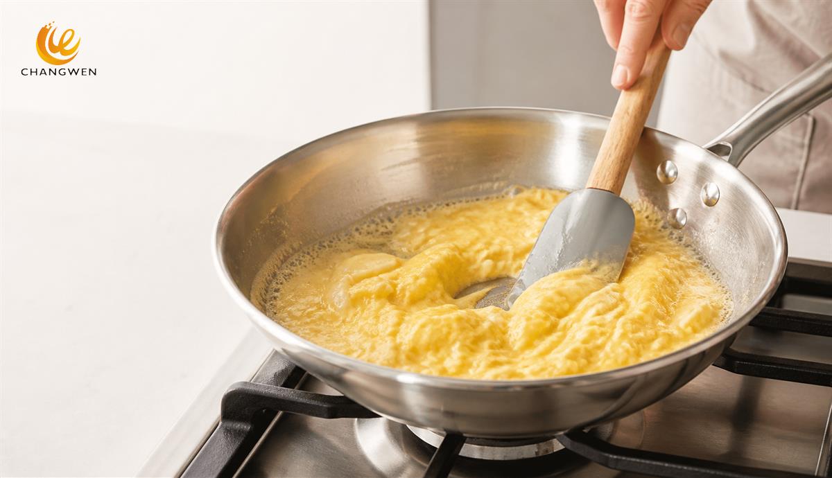 Soft scrambled eggs cooking in a stainless steel frying pan